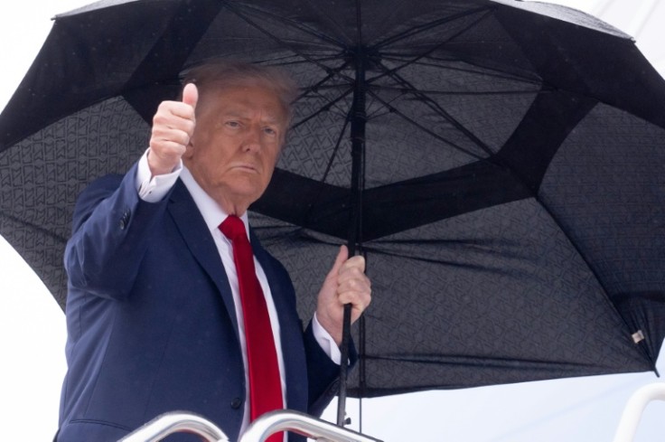 El presidente de Estados Unidos, Donald Trump, sostiene un paraguas y hace un gesto de aprobación con el pulgar al abordar el Air Force One antes de partir de la Base Conjunta Andrews en Maryland, el 12 de octubre de 2025.
