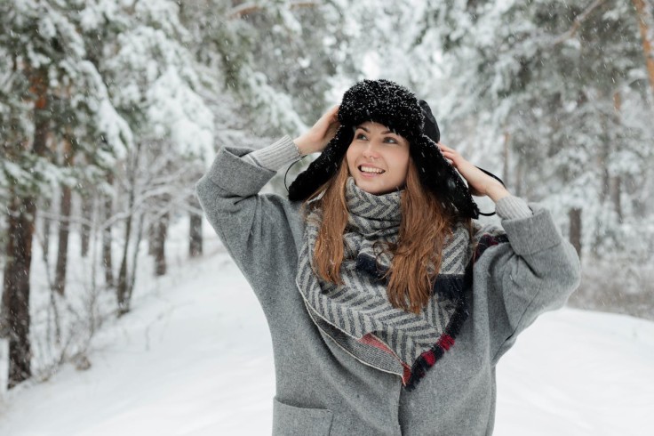 Mujer sonriente de pie junto a árboles cubiertos de nieve